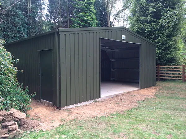 Large dark green steel garage with an open front