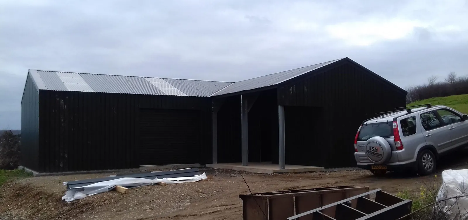 L-shaped dark clad steel building with an open bay